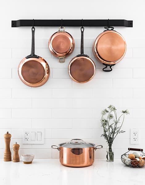 Copper cookware arranged in a warmly lit kitchen setting